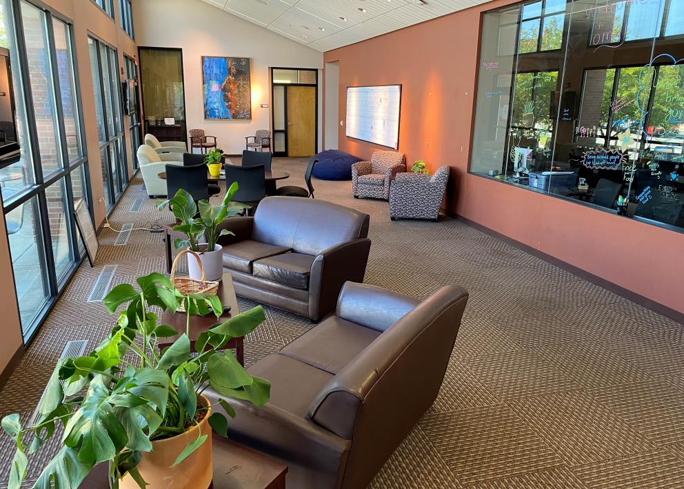 plants to brown couches are on the left in the foreground of the lobby with various chairs and a portrait of Dr. Martin Luther King Jr. hanging on the wall in the background